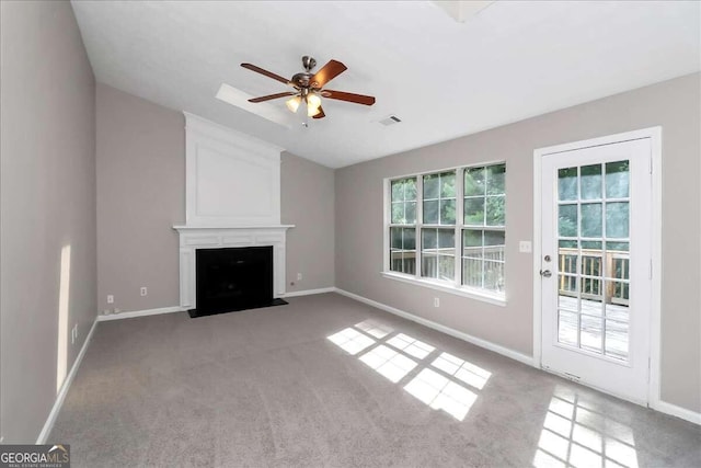 unfurnished living room with ceiling fan, a fireplace, and light carpet