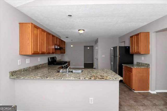 kitchen with kitchen peninsula, sink, a textured ceiling, and appliances with stainless steel finishes