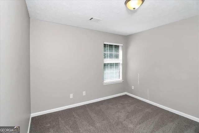 unfurnished room with dark colored carpet and a textured ceiling