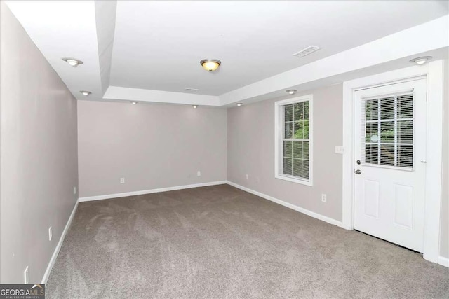 carpeted empty room with a raised ceiling