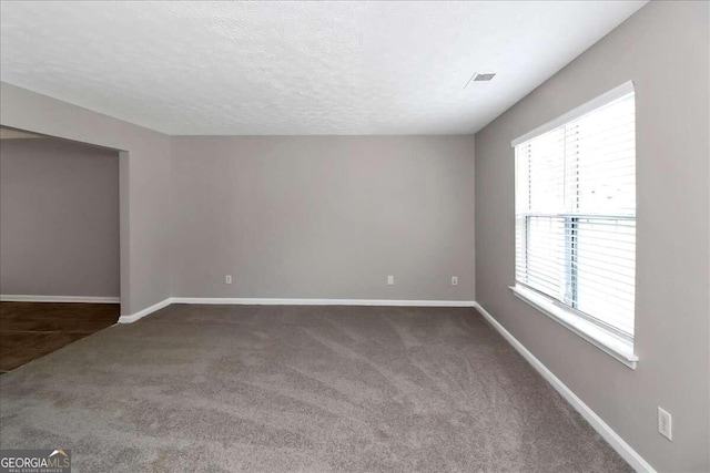 carpeted empty room with a textured ceiling