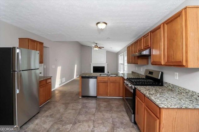 kitchen featuring light stone countertops, appliances with stainless steel finishes, vaulted ceiling, and ceiling fan