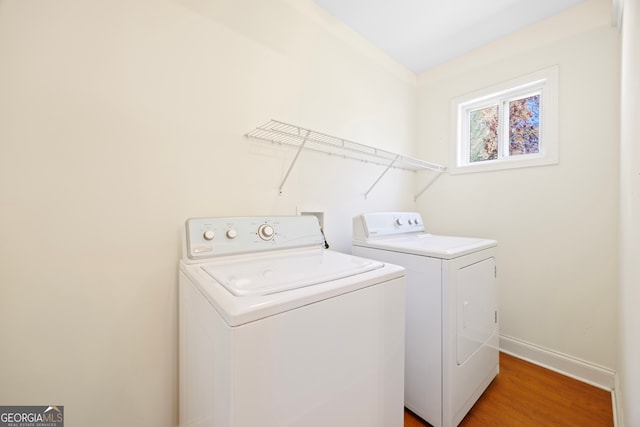 clothes washing area featuring washing machine and clothes dryer and hardwood / wood-style flooring