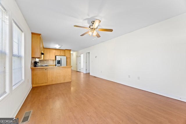 unfurnished living room with a wealth of natural light, light hardwood / wood-style flooring, ceiling fan, and sink