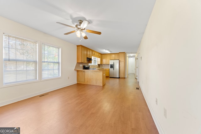 kitchen with kitchen peninsula, light brown cabinetry, stainless steel appliances, ceiling fan, and light hardwood / wood-style flooring