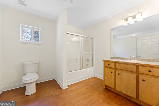 full bathroom with shower / bath combination with glass door, vanity, wood-type flooring, and toilet