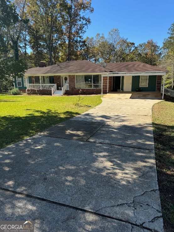 single story home with a front lawn, covered porch, and a carport