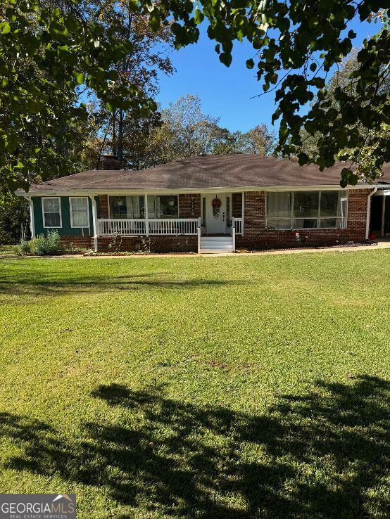 ranch-style house with covered porch and a front yard