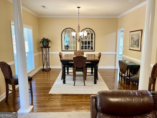 dining room with a textured ceiling, dark hardwood / wood-style floors, ornate columns, and crown molding