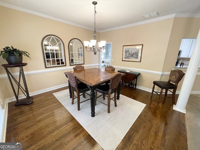 dining room featuring a notable chandelier, ornamental molding, dark wood-type flooring, and decorative columns