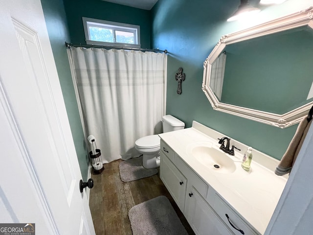 bathroom with hardwood / wood-style floors, vanity, toilet, and curtained shower