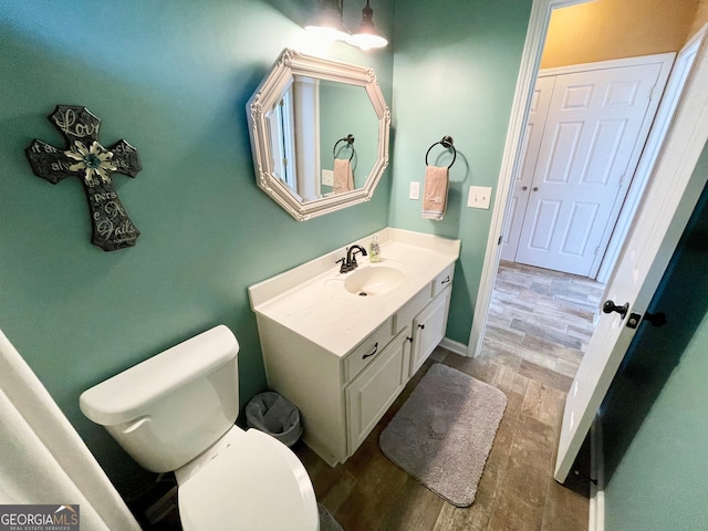 bathroom with hardwood / wood-style flooring, vanity, and toilet