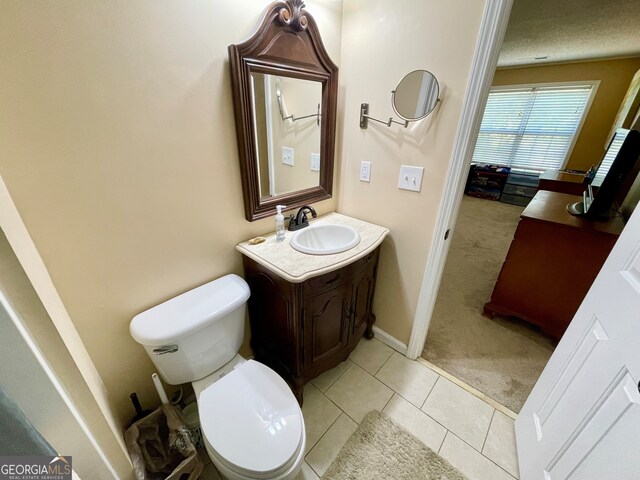 bathroom with tile patterned flooring, a textured ceiling, vanity, and toilet