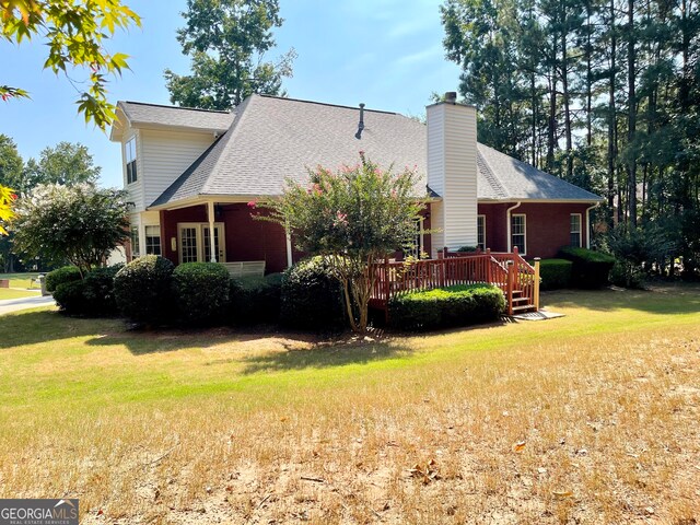 view of side of home with a yard and a deck