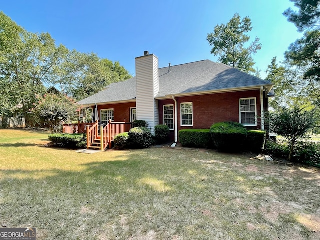 rear view of property with a deck and a yard