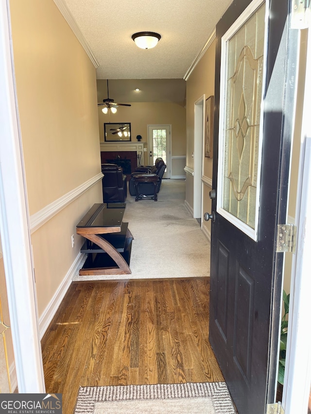 entryway with a textured ceiling, crown molding, ceiling fan, and dark hardwood / wood-style floors