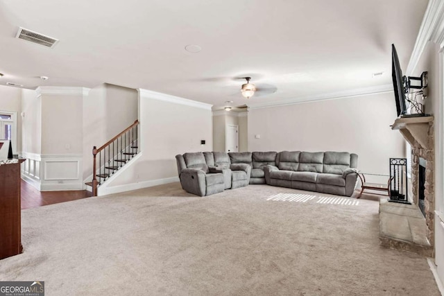 living room featuring hardwood / wood-style flooring, a stone fireplace, ceiling fan, and ornamental molding