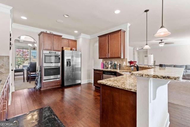 kitchen with kitchen peninsula, dark hardwood / wood-style flooring, stainless steel appliances, and decorative light fixtures