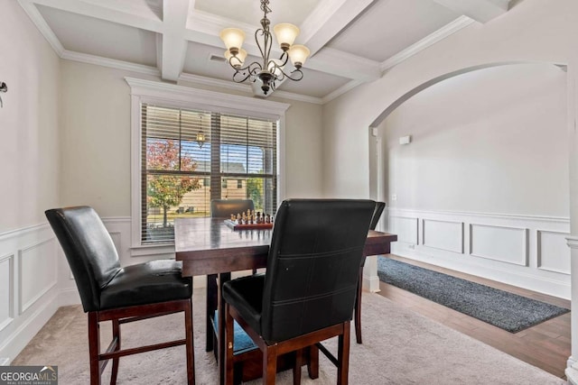 dining area with coffered ceiling, light hardwood / wood-style flooring, beamed ceiling, crown molding, and a chandelier