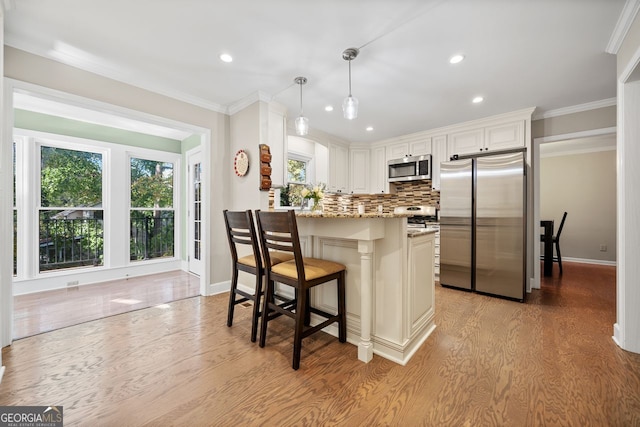 kitchen featuring light stone counters, light hardwood / wood-style flooring, pendant lighting, white cabinets, and appliances with stainless steel finishes