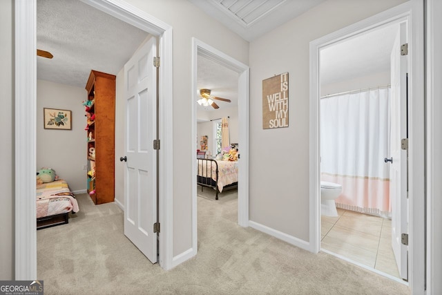 hallway with light colored carpet and a textured ceiling