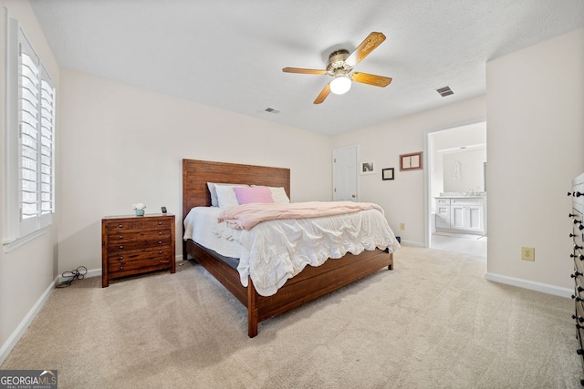 bedroom with ensuite bath, ceiling fan, and light colored carpet