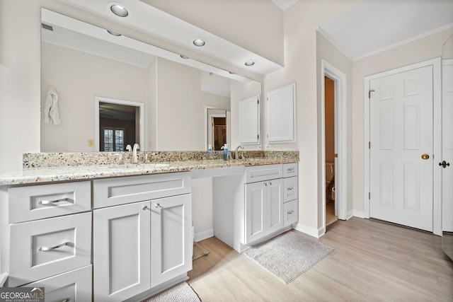 bathroom featuring vanity, wood-type flooring, and crown molding