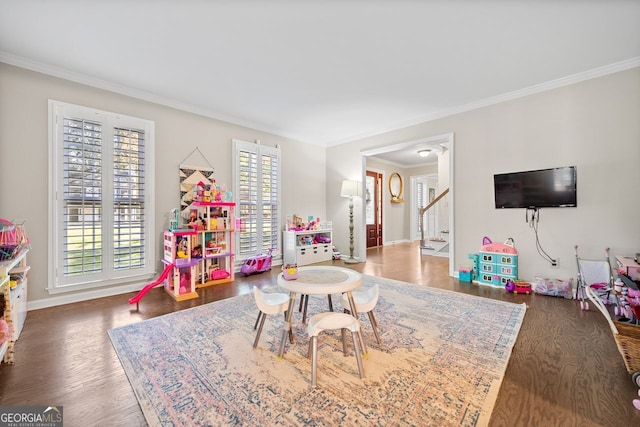 game room with dark wood-type flooring, a healthy amount of sunlight, and ornamental molding