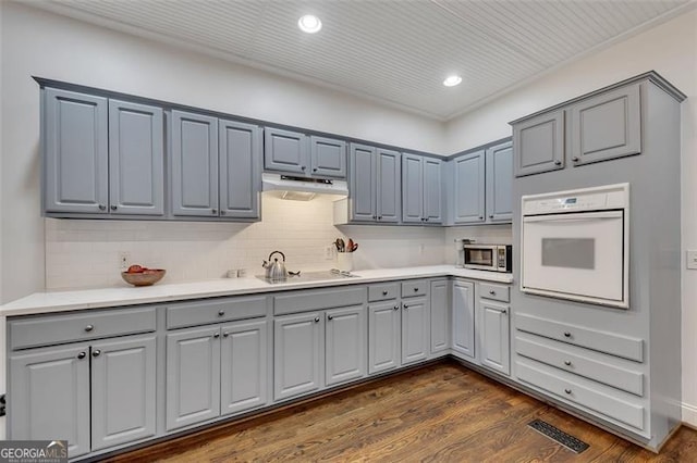 kitchen featuring black electric stovetop, white oven, gray cabinets, and dark wood-type flooring