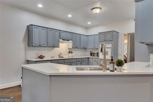 kitchen with tasteful backsplash, kitchen peninsula, dark hardwood / wood-style flooring, and gray cabinets