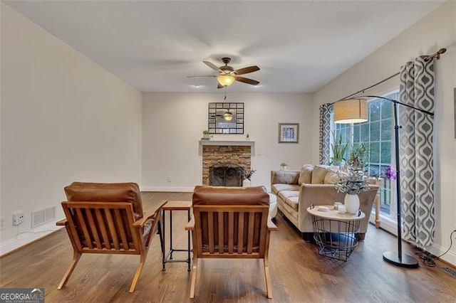 living room featuring ceiling fan, dark hardwood / wood-style flooring, and a fireplace