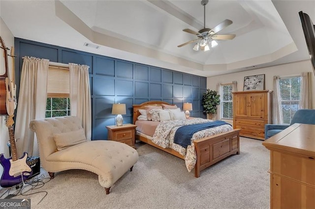 carpeted bedroom featuring a tray ceiling and ceiling fan