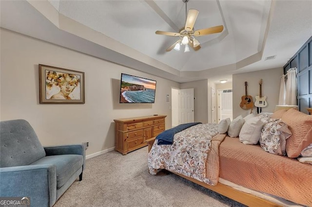 carpeted bedroom featuring a raised ceiling and ceiling fan