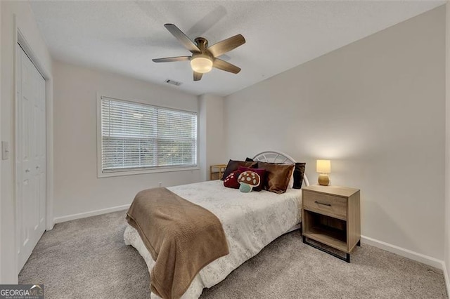 bedroom with ceiling fan, light colored carpet, and a closet