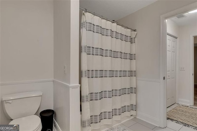 bathroom featuring tile patterned flooring, toilet, and walk in shower