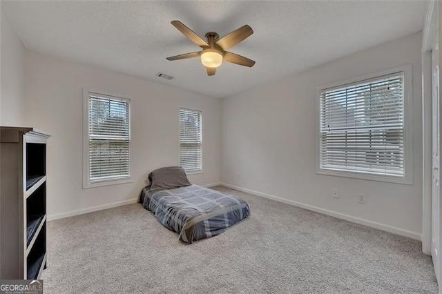 bedroom with multiple windows, ceiling fan, and light carpet