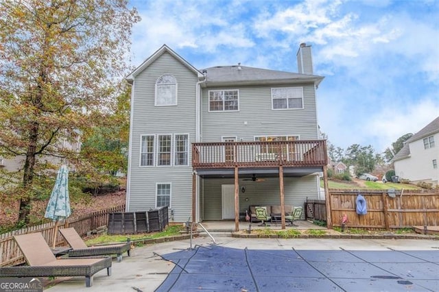 rear view of property with a swimming pool side deck, ceiling fan, and a patio area