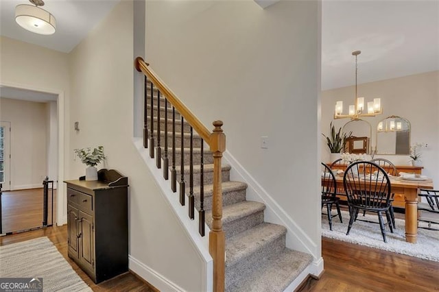 stairs with hardwood / wood-style flooring and an inviting chandelier