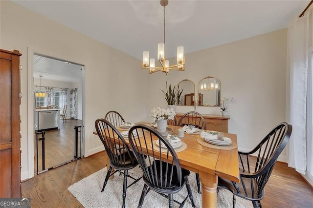 dining space with wood-type flooring and an inviting chandelier