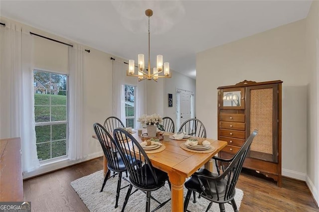 dining area with dark hardwood / wood-style flooring, plenty of natural light, and an inviting chandelier