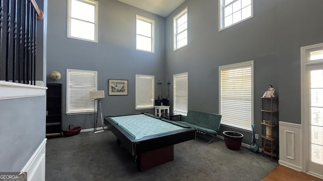 playroom featuring a high ceiling, dark colored carpet, and a healthy amount of sunlight