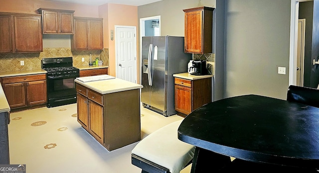 kitchen with tasteful backsplash, black gas stove, a center island, and stainless steel fridge with ice dispenser