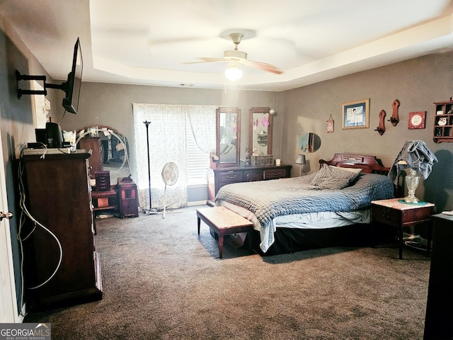 carpeted bedroom with a raised ceiling and ceiling fan