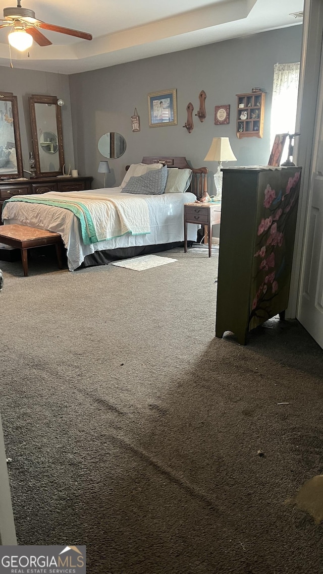 bedroom featuring a raised ceiling, carpet flooring, and ceiling fan