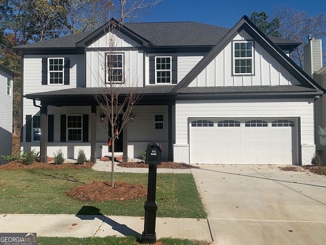 view of front of home featuring covered porch, a garage, and a front lawn