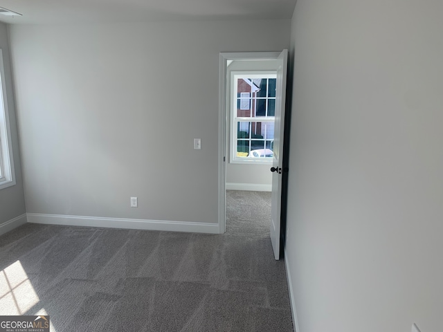 spare room with dark colored carpet