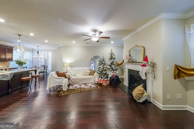 living room featuring ceiling fan with notable chandelier, dark hardwood / wood-style floors, and crown molding