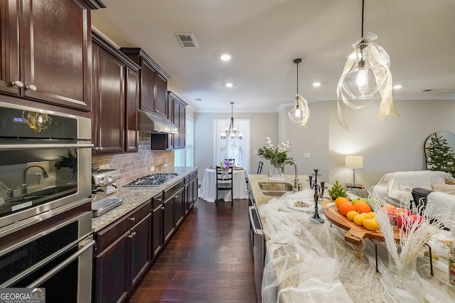 kitchen with light stone countertops, appliances with stainless steel finishes, sink, decorative light fixtures, and dark hardwood / wood-style floors