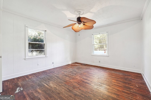 empty room featuring a wealth of natural light, dark hardwood / wood-style flooring, ceiling fan, and crown molding