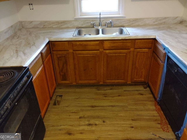 kitchen with sink, black appliances, and light hardwood / wood-style flooring